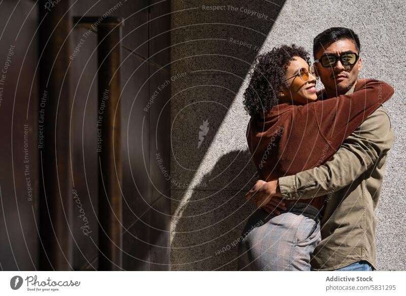 Multiethnic couple sharing a tender embrace in Madrid's sunny streets love multicultural happiness madrid spain diversity sunglasses style fashion chinese