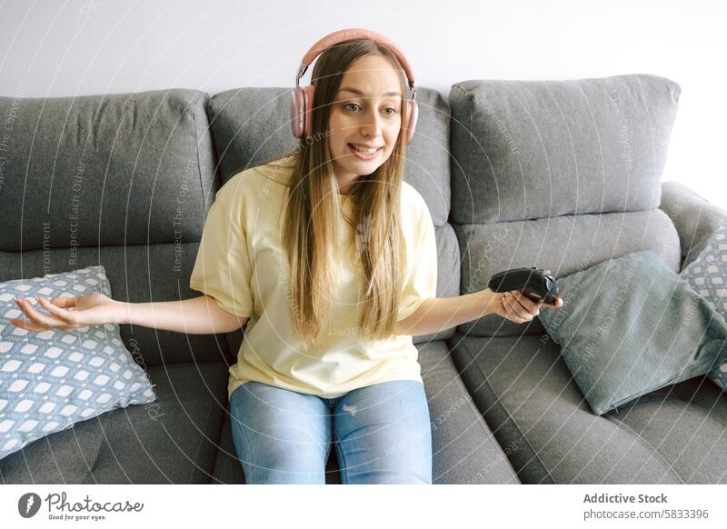 Woman enjoying video games on a cozy sofa woman gaming home leisure entertainment headset headphones couch comfortable sitting enjoyment fun play controller