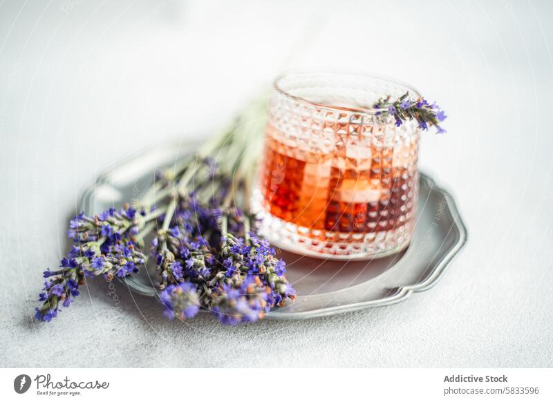 Elegant cognac cocktail adorned with fresh lavender beverage drink alcohol luxury glass sprig garnish tray silver textured sophisticated rustic elegant serve