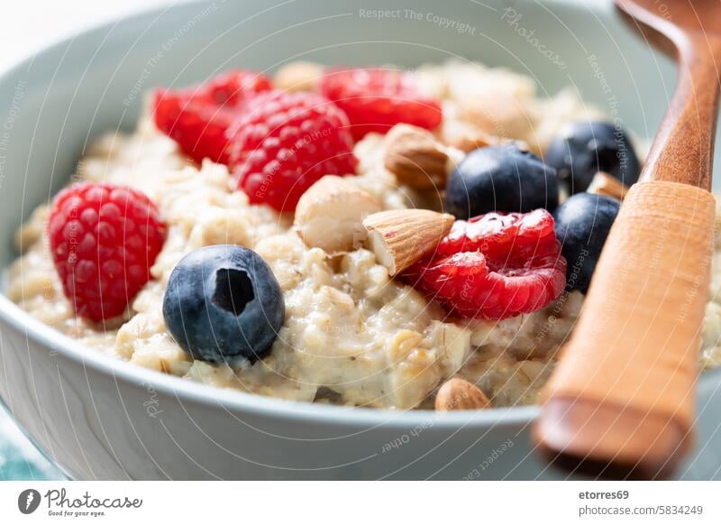 Oatmeal porridge with raspberries, blueberries and almonds in bowl on wooden table black breakfast energy food fruit healthy mix nutrition nuts oatmeal
