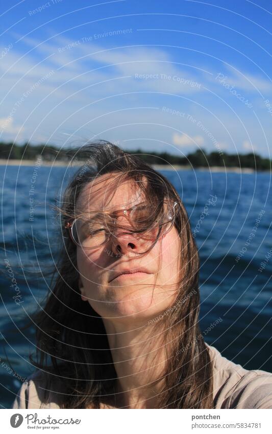 a woman in a boat with her eyes closed in front of the sea. relaxation, recreation, enjoyment Survive Head Woman Human being Ocean Water Eyeglasses Breeze