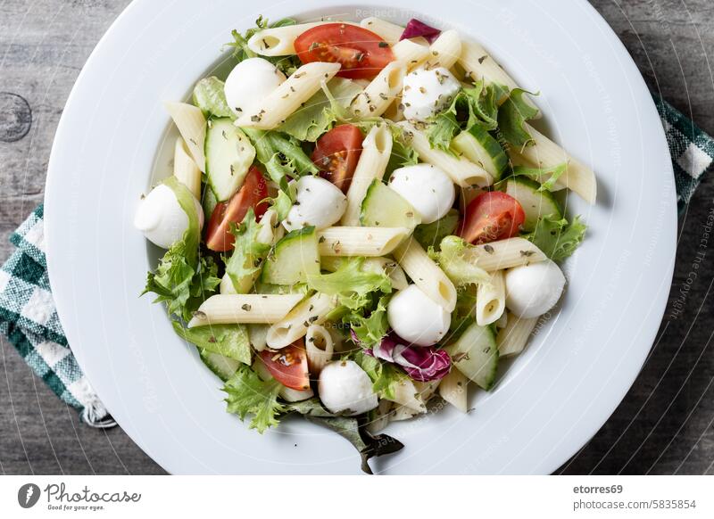 Pasta salad with vegetables and mozzarella cheese on wooden table cucumber dish healthy ingredient lettuce macaroni meal nutrition pasta pasta salad plate