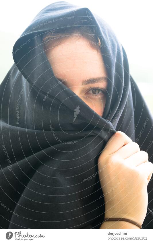 Young woman with a veiled scarf over her head, so that only one eye and one hand can be seen. Headscarf Adults Colour photo portrait Face Woman Human being