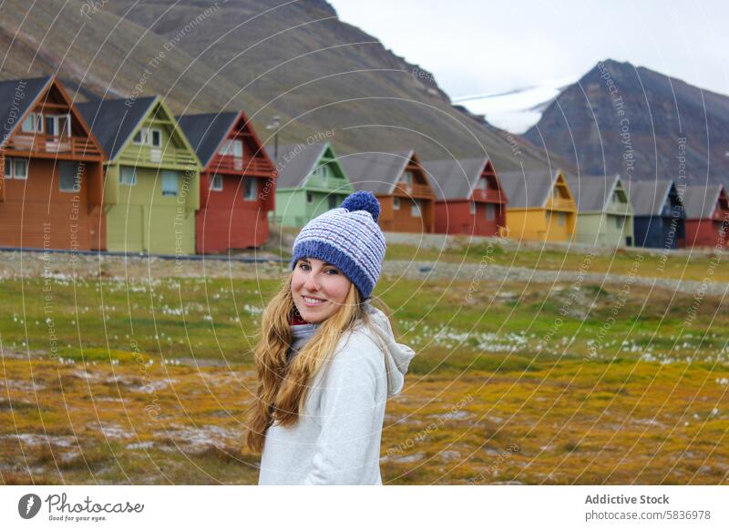 Young tourist woman in Longyearbyen, Svalbard. Summer time adventure travel in Norwegian Arctic. svalbard norway colorful houses beanie smiling