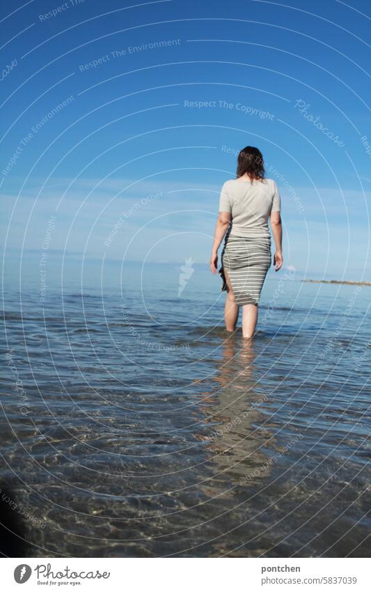 a clothed woman waters in the sea. Ocean wade Refreshment enjoyment Woman Water Wet Vacation & Travel Joy Skirt fashionable Back Body Exterior shot Sky Blue