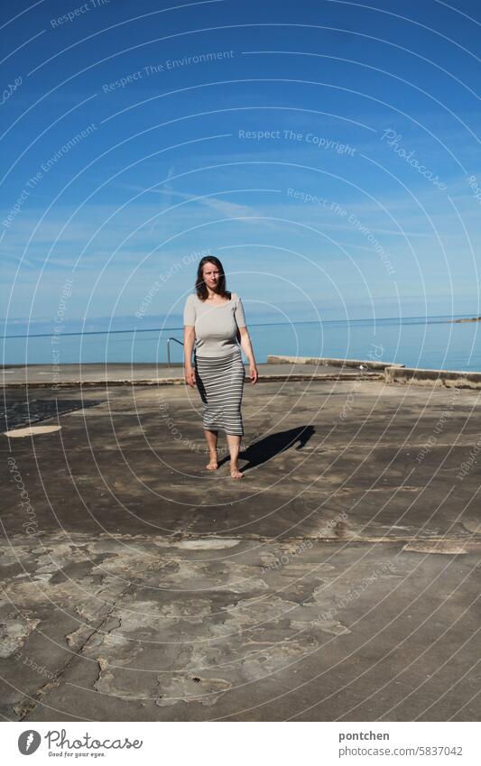 a woman walks across a concrete slab by the sea. relaxing, recovering. Ocean holidays Happiness Caucasian Life Woman Nature Lifestyle Body Vacation & Travel