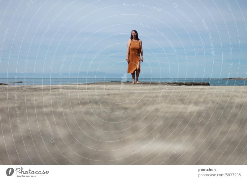 woman on a concrete jetty by the sea. Ocean vacation Footbridge holidays Dress Happiness Caucasian Life Woman cloudy Nature Lifestyle Body Vacation & Travel