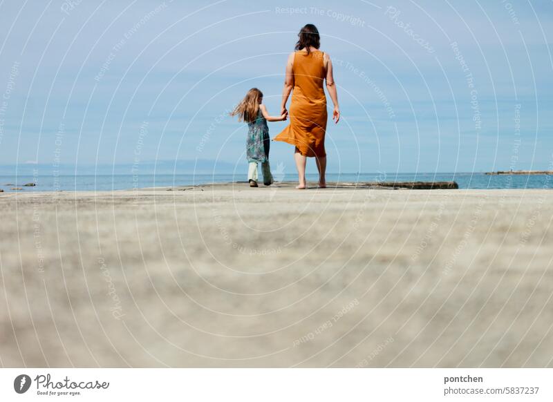 Mother and child walk hand in hand along a jetty by the sea. Child Love Hold hands Happy Together Family & Relations Feeling of togetherness Mother with child