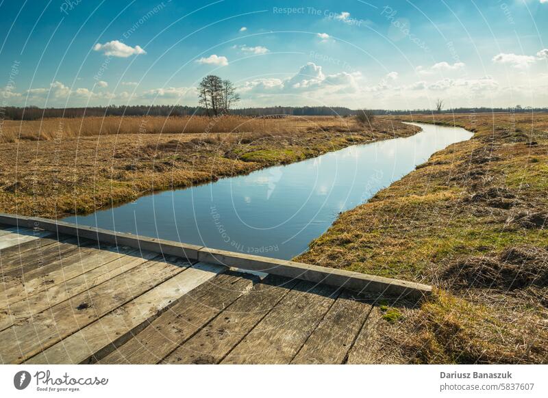 A wooden bridge on a small river poland footbridge sky tree horizon grass calm meadow landscape horizontal photography nature day water connection europe