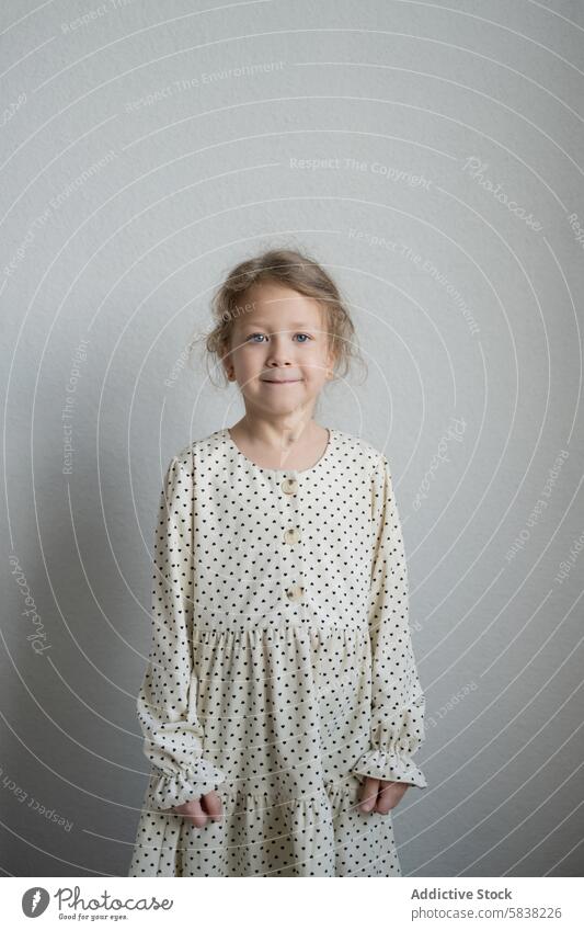 Young girl in polka dot dress smiling at the camera young portrait smile child plain background standing gentle fashion innocence joyful kid female youth happy