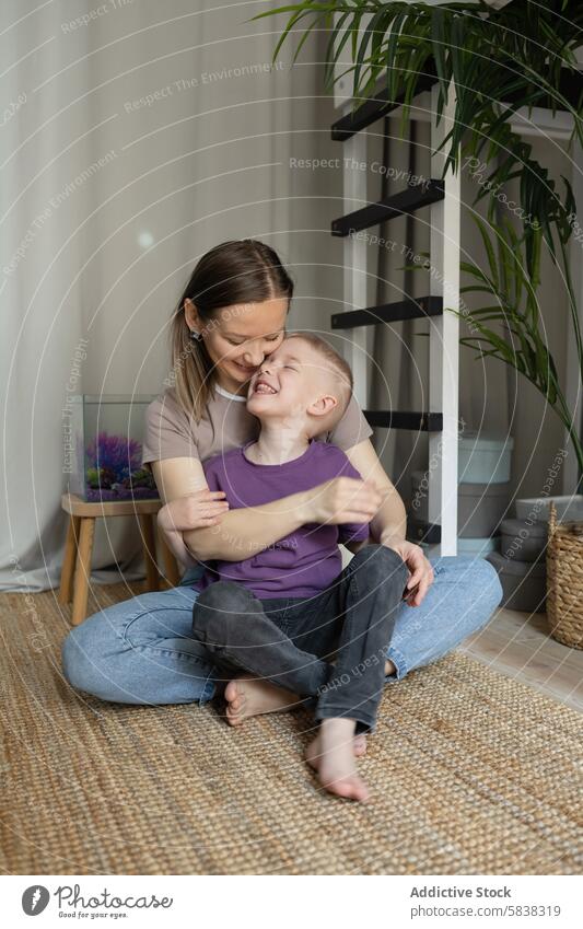 Tender moment between mother and child indoors son hug laugh home family warmth bond carpet fish tank cozy love joy maternal care affection embrace happiness