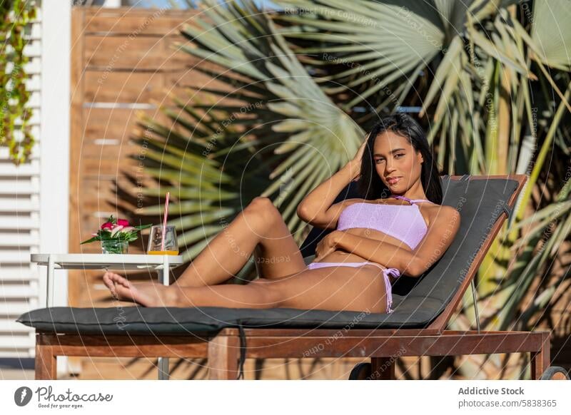 Relaxed Latin Woman Enjoying Summer Day Poolside woman latin summer poolside sunbed relax leisure swimsuit bikini sunbathing tropical drink looking away daytime