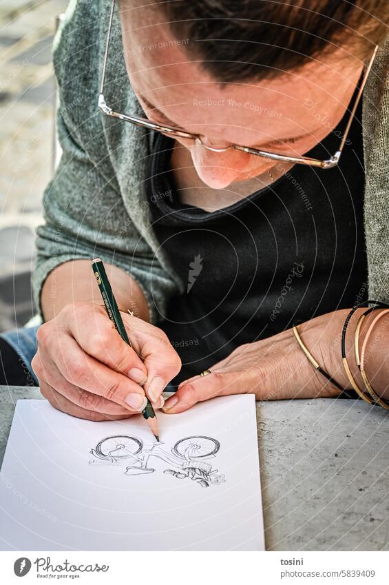 Woman draws a bicycle on paper with a pencil Art Hand Draw Fingernail Pencil Creativity Paper Artist Leisure and hobbies Close-up Painter Colour photo Drawing
