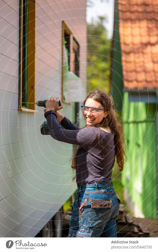 Young woman using a drill on a farm building outdoors young diy construction smile smiling drilling sunny happy female cheerful work manual labor renovation