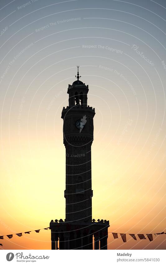 The clock tower of Izmir with flags and pennants in the light of the setting sun at Konak Square in old Smyrna on the Aegean Sea in Turkey Asia Minor Anatolia