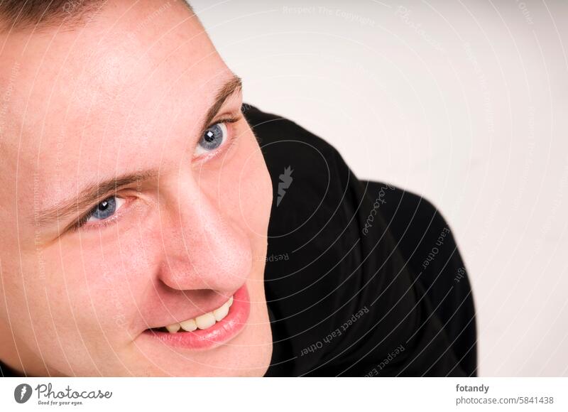 Close-up of a young smiling Caucasian man in an elevated side view looking upwards to the right against a white background. person Man Partially visible Smiling