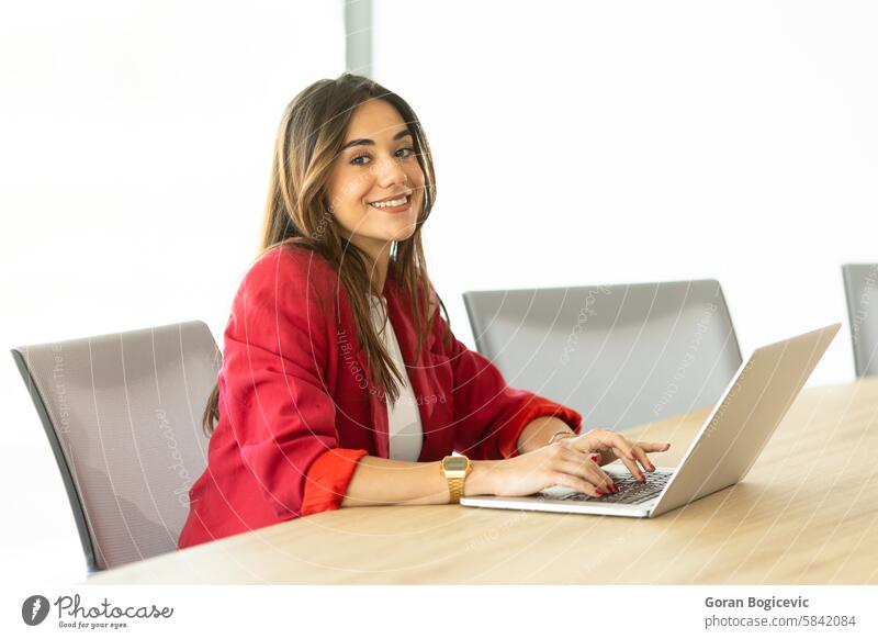 Confident businesswoman smiling during morning meeting in modern office conference table red blazer laptop confident cheerful professional work workplace