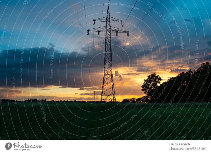 Power pylons and cables lead the view far into the picture. The evening sky is already getting dark Electricity pylon power line Power transmission stream