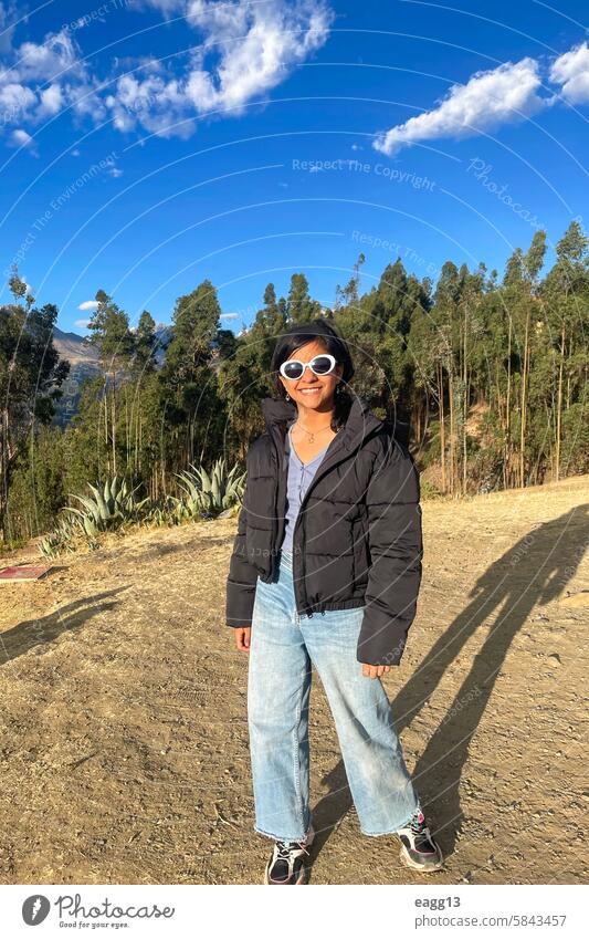 A woman wearing sunglasses and a black jacket stands in front of a forest teenager person beautiful travel old symbol business design outdoors fashion tourist