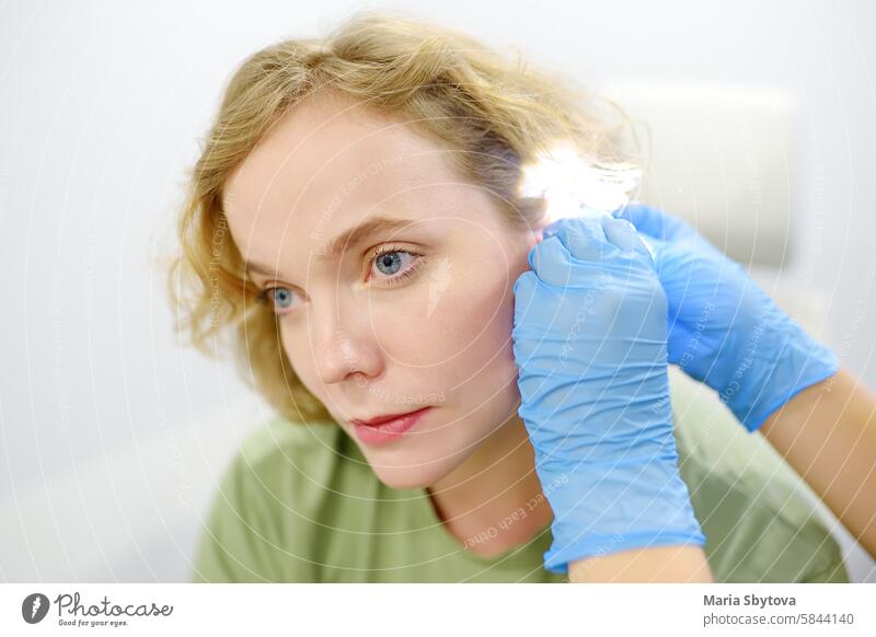 A patient is seen by an otolaryngologist. A professional ENT doctor examines a patient. An otolaryngologist examines a patient's inner ear using an otoscope