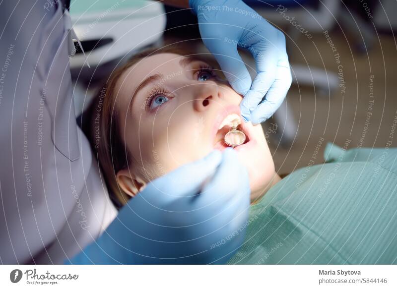 Dentist and patient at modern medical center. Doctor treats a young woman teeth in hospital. Practitioner examines the patient before orthodontists or prosthetics treatment.