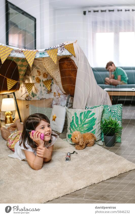 Two happy children talking with walkie-talkie at in cozy tent. Vacation camping at home concept. playing call shelter girl lying carpet rug handmade teepee boy
