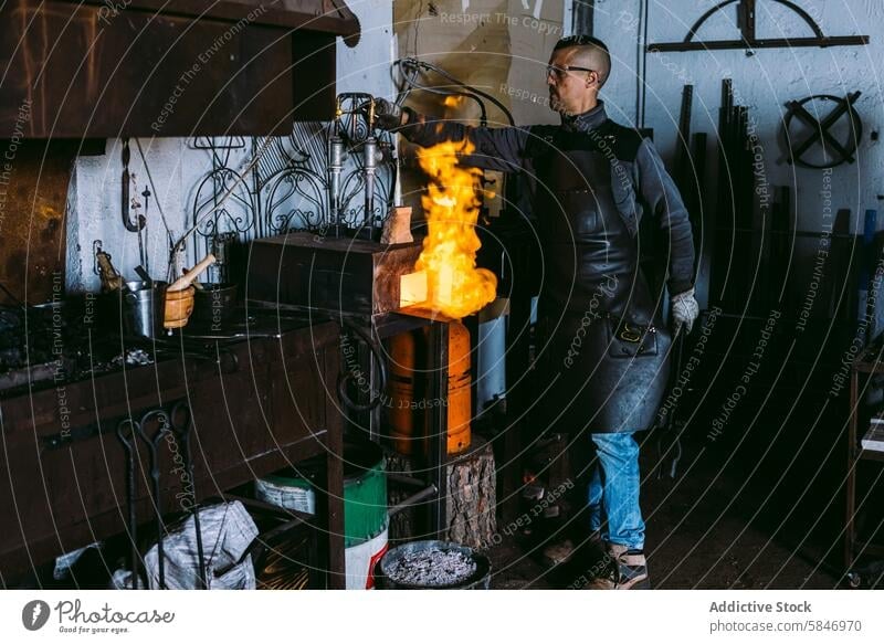 Blacksmith working with molten metal in forge blacksmith male workshop fire equipment profession craft blaze heat artisan manual labor safety goggles leather