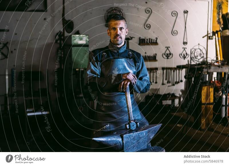 Confident Blacksmith Standing in His Workshop blacksmith male workshop smithy anvil hammer industrial craft handcraft metalwork fabrication professional