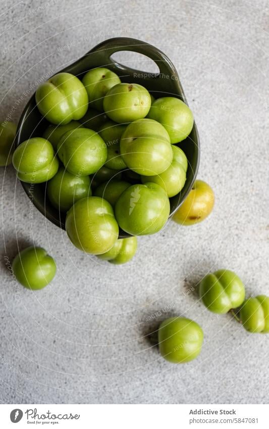 Fresh organic green plums in ceramic bowl on gray background ripe fruit mediterranean texture scattered surface fresh culinary cuisine georgia turkey greece