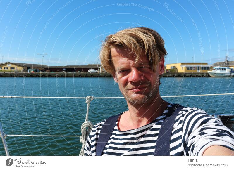 a man on a boat in the harbor Harbour Denmark Man Sailor shirt Water Exterior shot Maritime Sailing Blonde Colour photo Spring Sailboat rail Baltic Sea Sky