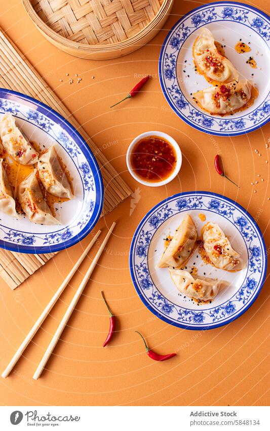 Asian Dumplings with Spicy Chili Sauce on Decorative Plates Asian flavors Culinary Serving appetizer authentic bamboo steamer blue and white plates chili dip