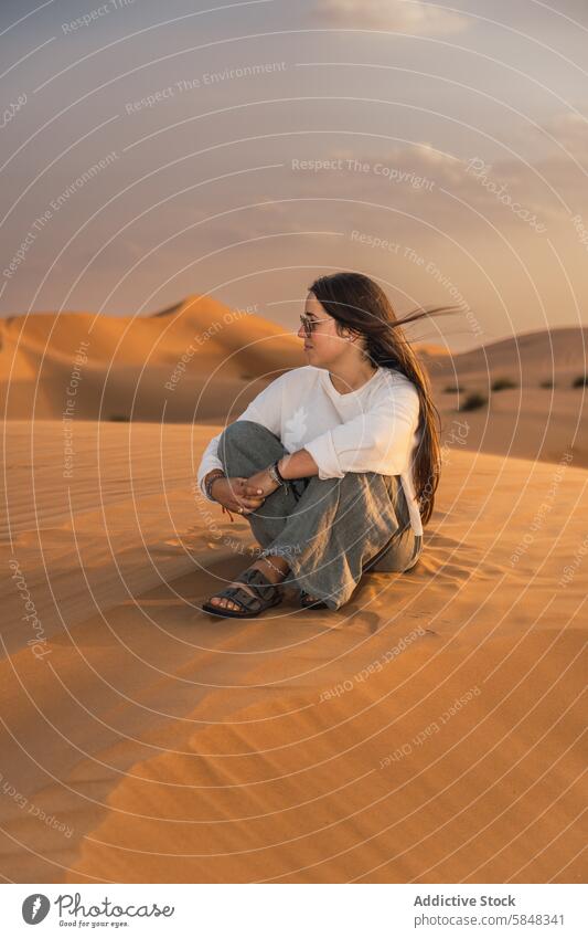 Woman serene desert sunset moment in Oman tranquility solitude golden sand sitting woman peaceful nature travel journey dune relaxation outdoors excursion