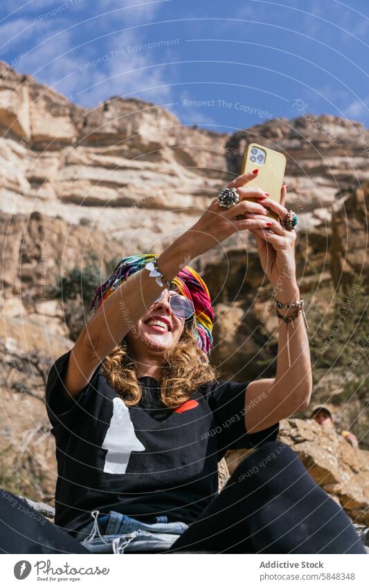 Joyful woman taking selfie on Oman mountain trip smartphone traveler cheerful adventure rugged backdrop discovery joy capture spirit tourism nature outdoors