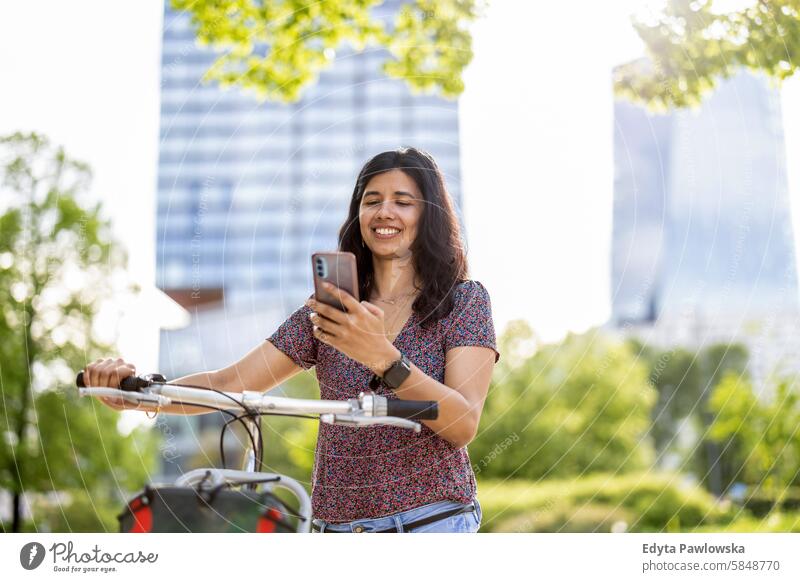 Young woman using her smartphone while out cycling through the city Indian real people fun summer enjoying street travel outdoors urban adult young adult