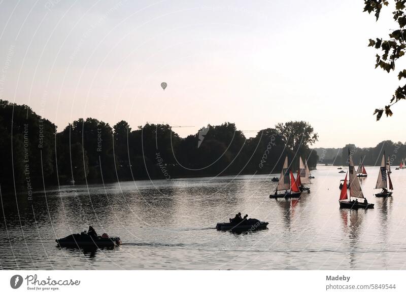 Colorful sailboats and dinghies as well as a hot air balloon in the light of the evening sun on the Aasee in Münster in Westphalia in Münsterland Weekend