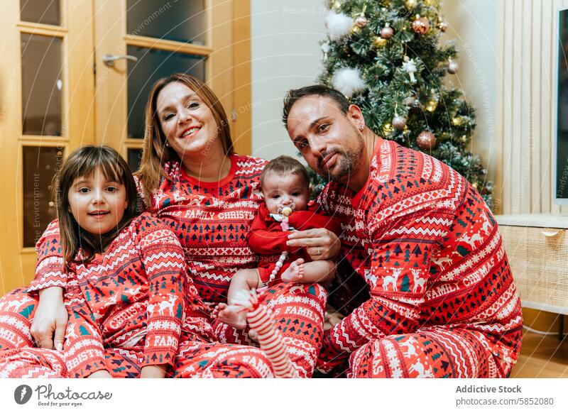 Cozy family Christmas moment with matching outfits christmas matching pajamas smiling cozy holiday festive season tradition children parents mother father baby