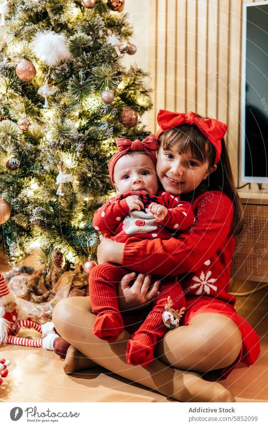 Siblings celebrating Christmas together at home family christmas celebration siblings girl baby festive red outfit decorated christmas tree happy holiday season
