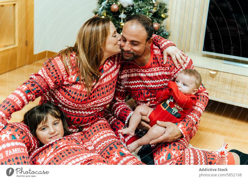 Family sharing a tender moment during Christmas celebration family christmas red pajamas matching loving newborn decorated tree festive holiday tradition