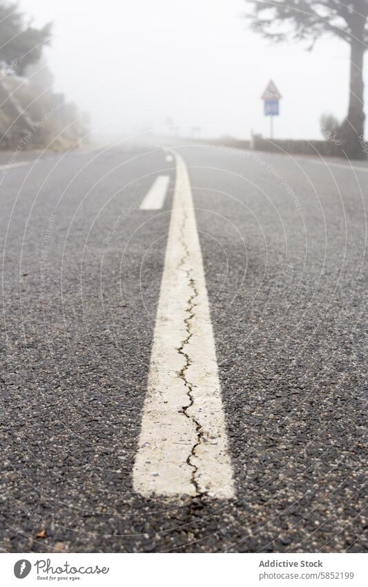 Mysterious foggy road with faded lines and warning sign mystery white line caution mist quiet shroud view looming atmosphere travel journey asphalt pavement