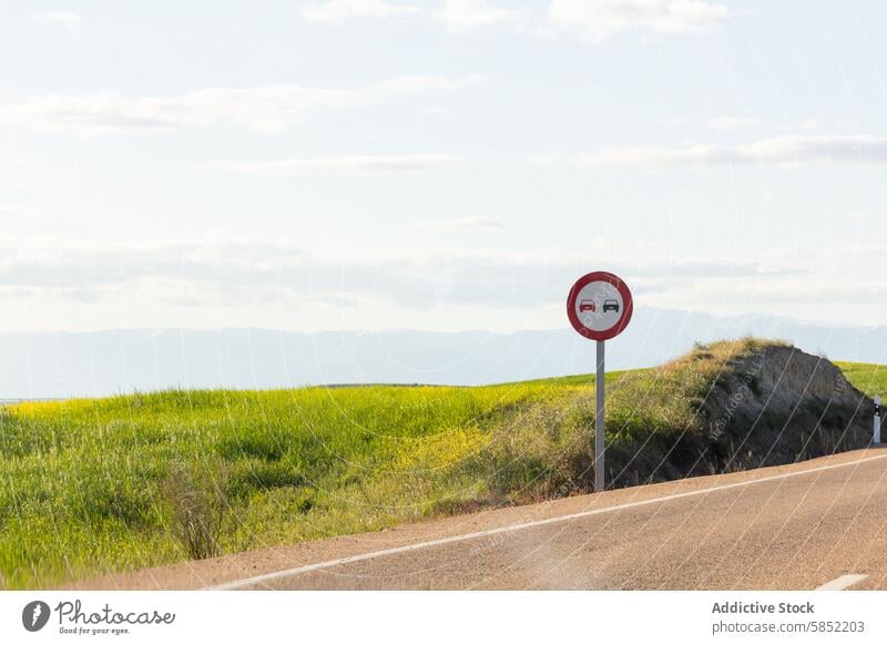Scenic road landscape with a no overtaking sign country green field clear sky scenic tranquil traffic sign road safety travel highway rural nature horizon