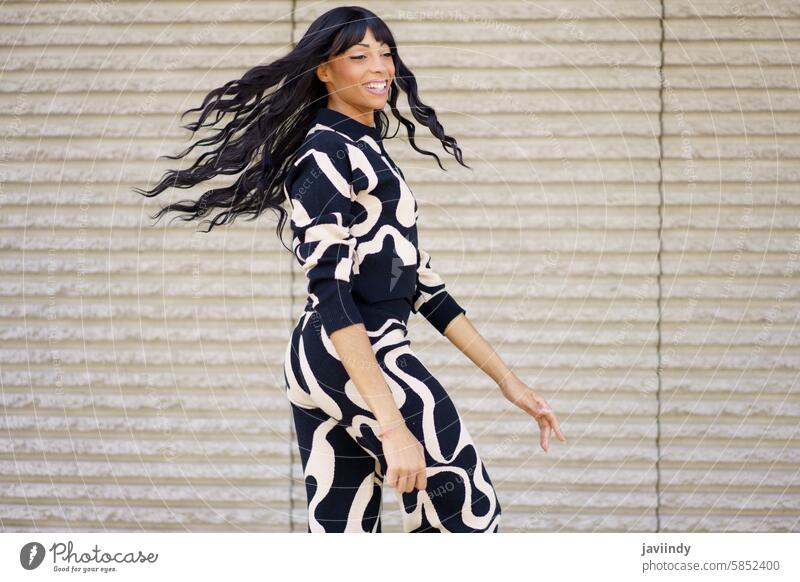 Dancer turning moving her long hair dancing in the city hispanic happy energetic beauty woman dancer urban concrete grey wall joyful movement vibrant dynamic