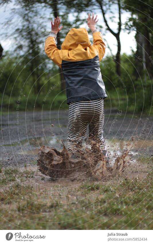 Fun in the giant puddle Child Rainwear slush pants Puddle Hop Jump Playing Rubber boots Sludgy Water splashing Joy fun muck about Meadow Gravel path Summer Wet