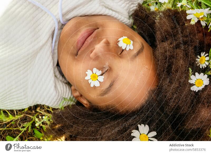 Young girl relaxing in park with daisies on her face daisy nature relaxation tranquility peaceful grass lying down serene outdoor leisure natural light spring