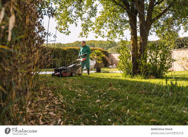 Man mowing a lush green lawn in a serene garden man uniform lawn mower trees plants outdoor activity gardening landscaper work nature peaceful maintenance