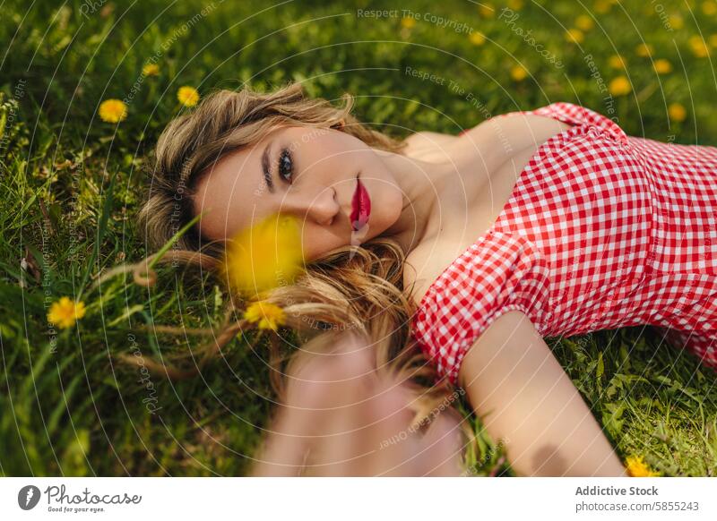 Young woman lying in a grassy field with flowers nature park relax cheerful green smile tranquility sunny spring outdoors youth peace beauty leisure refreshment