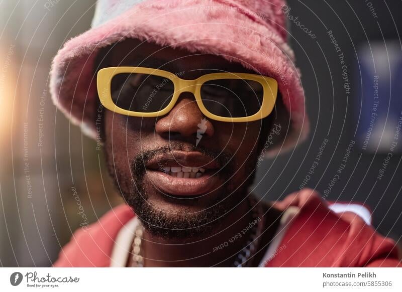 Black Man Wearing Retro Sunglasses and Pink Outfit Black man pink hip-hop sunglasses rapper look at camera record video bucket hat influencer performer