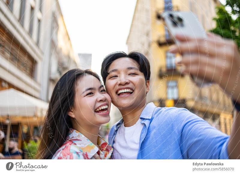 Smiling young couple using mobile phone in the city Asian real people fun enjoying young adult Authentic Cheerful Self-confident Woman Happy Joy Millennia