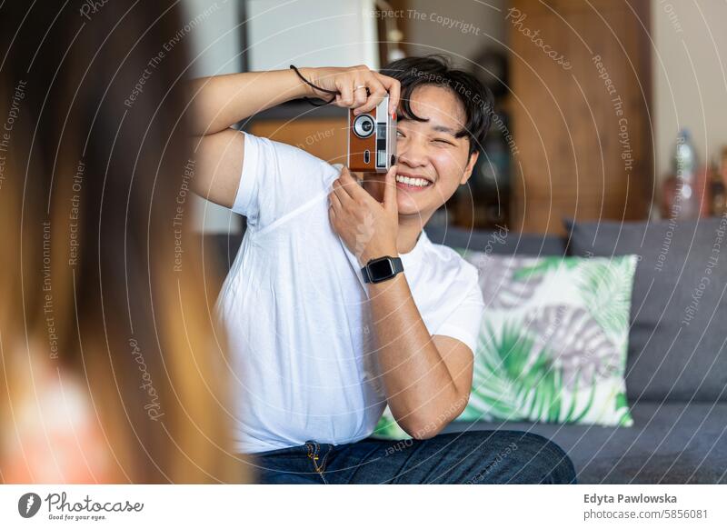 Young man photographing his girlfriend at home asian real people fun enjoying young adult authentic cheerful confident female happy millennials natural portrait