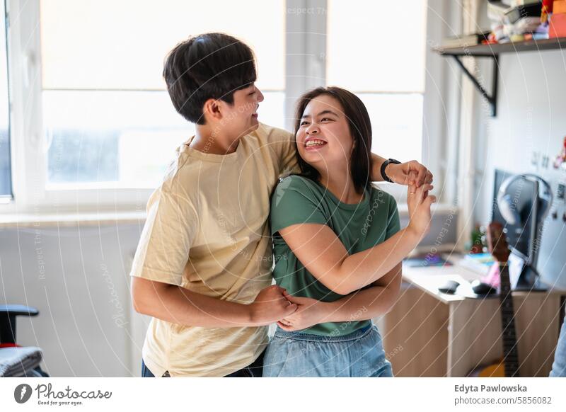 Happy young couple enjoying dancing together at home asian real people fun young adult authentic cheerful confident female happy millennials natural portrait