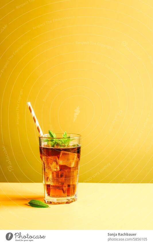 Iced tea in a glass with ice cubes and peppermint. Still life, summer drink. drinking glass Ice cube Cold yellow background variegated Modern Still Life